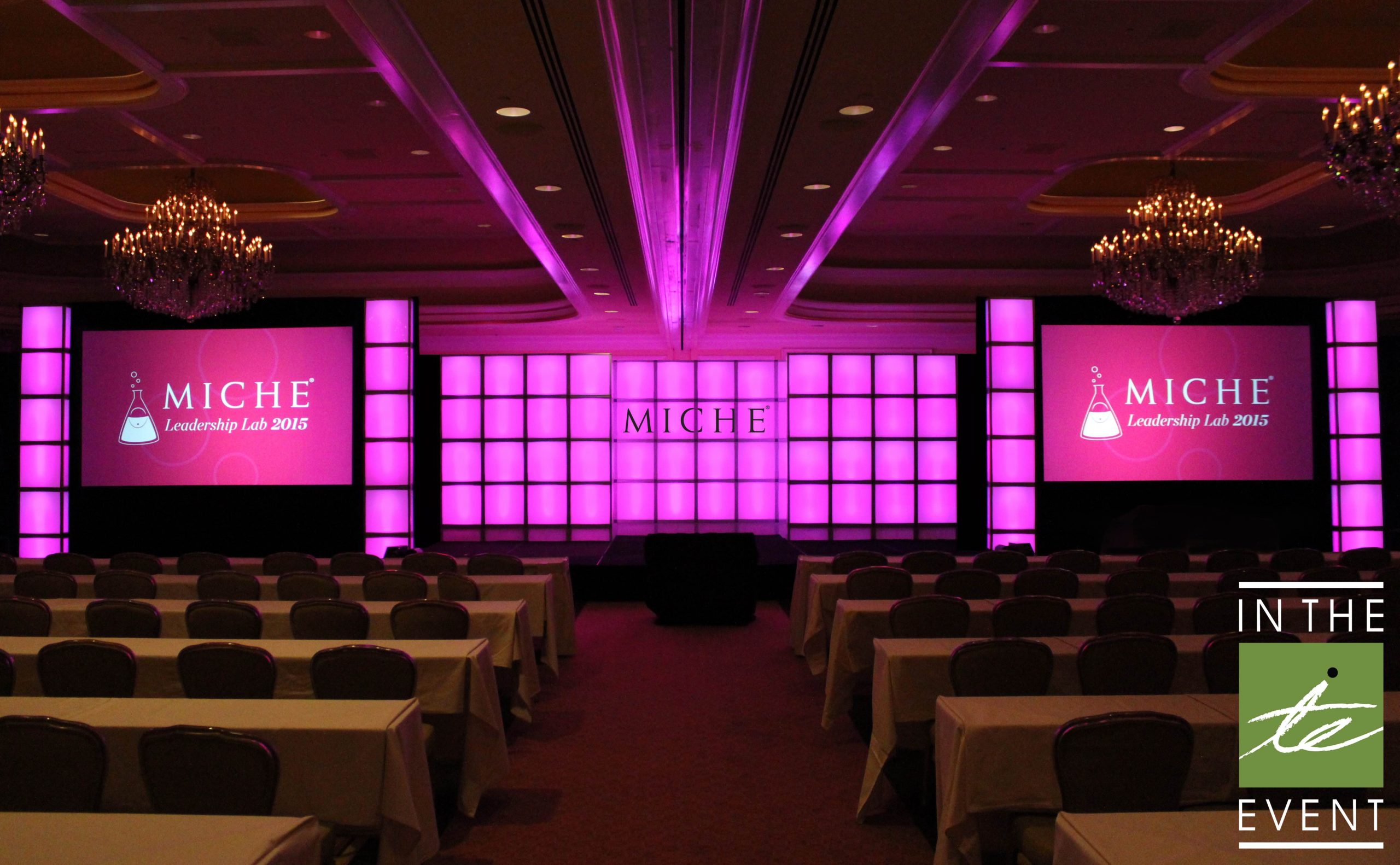 Miche Leadership Lab 2015 stage with illuminated modular backdrop, dual projection screens, and elegant seating setup.
