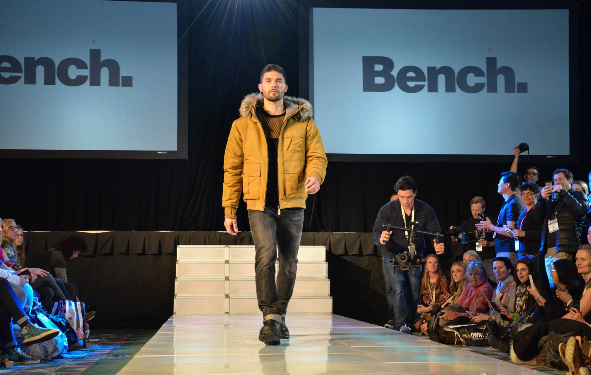 Fashion model walking down a runway with Bench branding, professional staging, and live event production setup