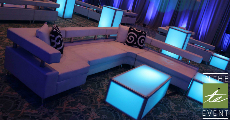 White sectional lounge seating with glowing blue LED coffee table and accent cubes, modern event furniture rental by In The Event.