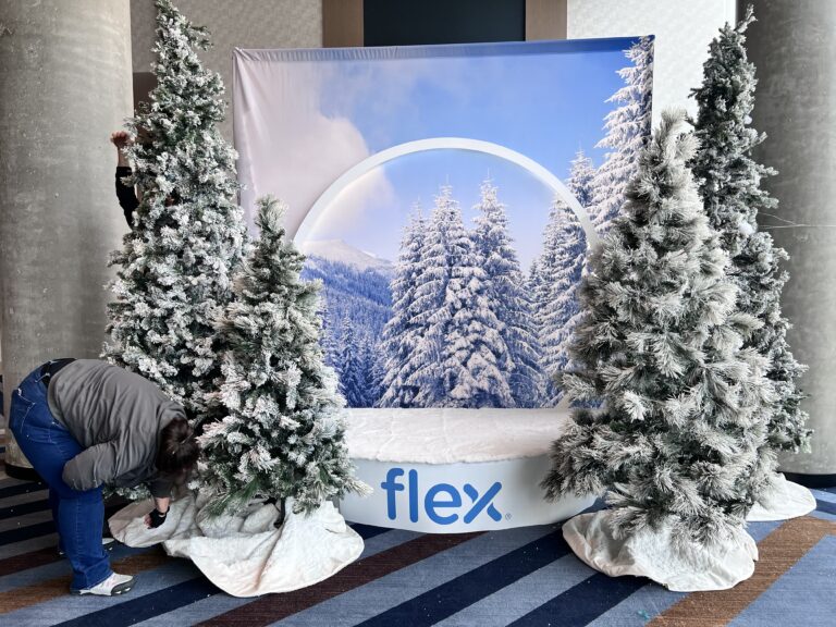 Branded winter-themed photo backdrop with snow-covered trees and frosted Christmas trees.