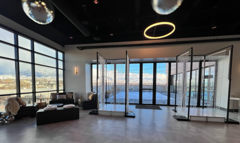 Modern event space with mountain views, lounge seating, and a beaded crystal photo backdrop.