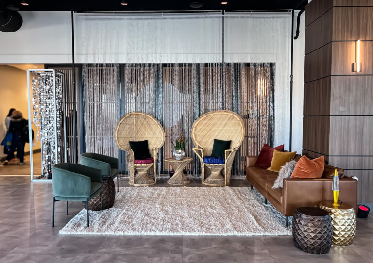 Boho-inspired lounge setup with peacock chairs, velvet seating, and a beaded curtain backdrop.