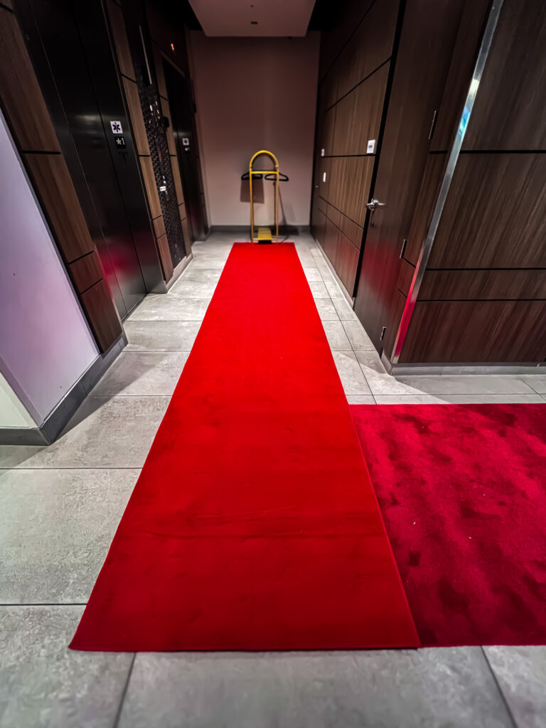 Red carpet rolled out in a modern hallway for event entrance.