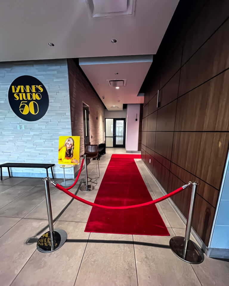 Red carpet entrance with custom “Lynne’s Studio 50” signage and a portrait on display.