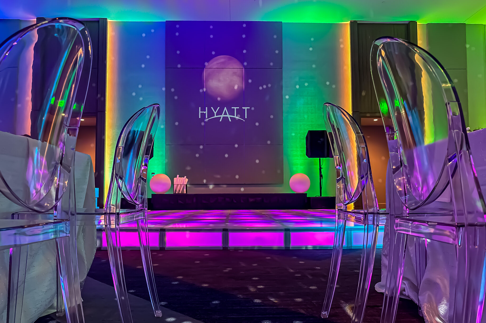 LED light-up dance floor with acrylic chairs and colorful space-themed uplighting for rent.
