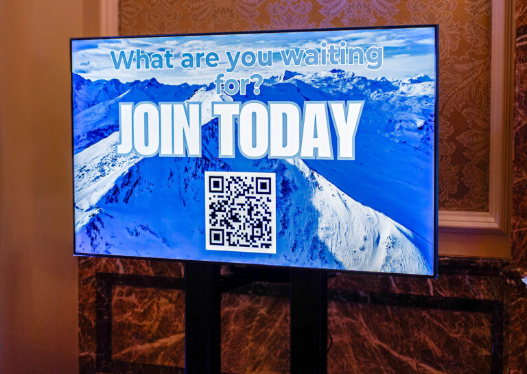 Digital display featuring a snowy mountain background with the bold message “What are you waiting for? Join Today” and a scannable QR code.