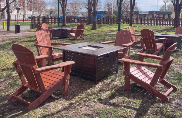Folding Adirondack chairs with fire tables set up for outdoor lounge seating at a park event.