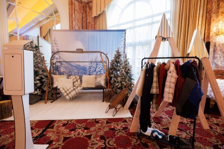 Winter-themed photo booth with snowy backdrop, swing bench, sleds, and coat rack at the Salt Lake City NACE Launch Event 2024