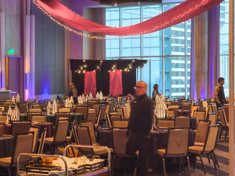 Event staff finalize table settings and backdrop setup for the SILAC Insurance Gala