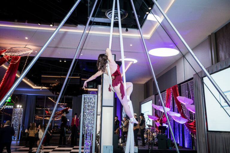 Aerial silk artist performs midair during SILAC Insurance Gala in a burgundy costume