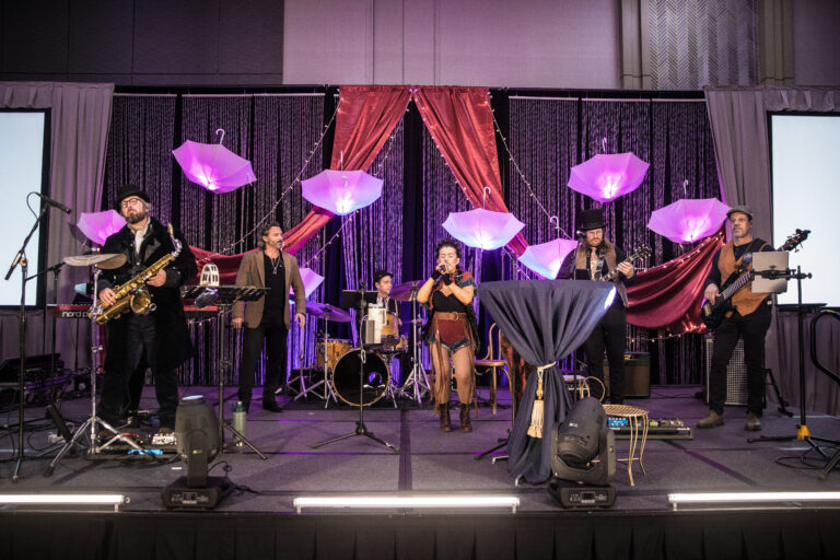 Live band performs beneath glowing umbrellas and red drapes at the 2024 SILAC Insurance Gala