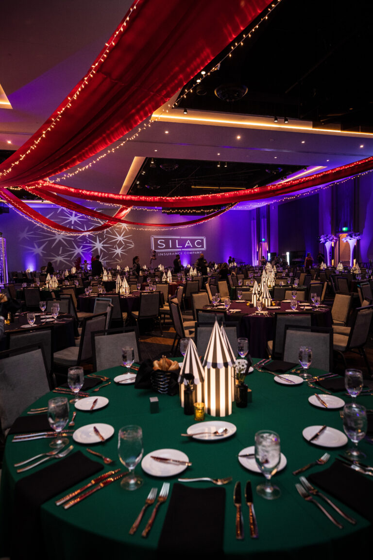 Close-up of gala table with green linen and striped tent-style centerpiece under red draped ceiling