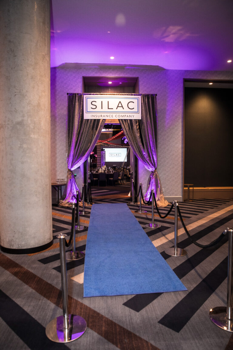 Blue carpet leads to a silver draped entry with branded signage at the SILAC Insurance Gala 2024