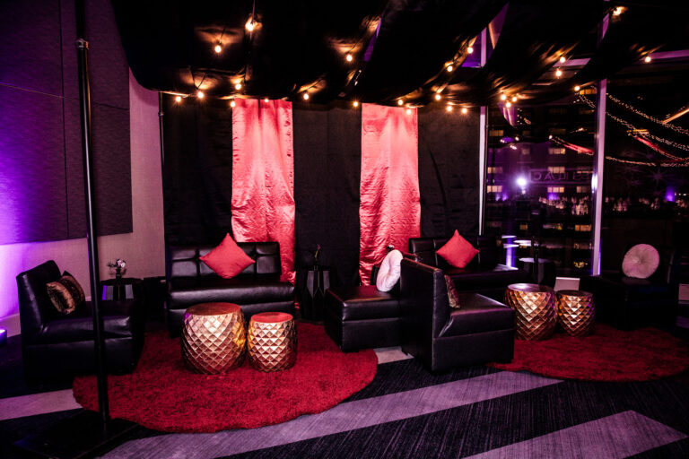 Event lounge setup with black leather furniture, red pillows, accent tables, and drapery at the SILAC Insurance Gala 2024