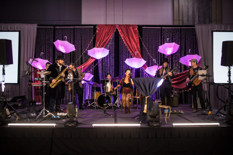 Live band performs on a decorated stage with glowing umbrellas and drapery at the SILAC Insurance Gala 2024