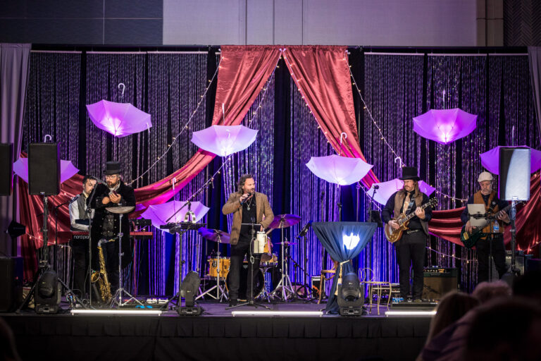 Live band performs on a decorated stage with illuminated umbrellas and red drapery at SILAC Insurance Gala 2024