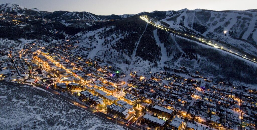 Aerial winter view of Park City, Utah with illuminated Main Street and ski slopes.