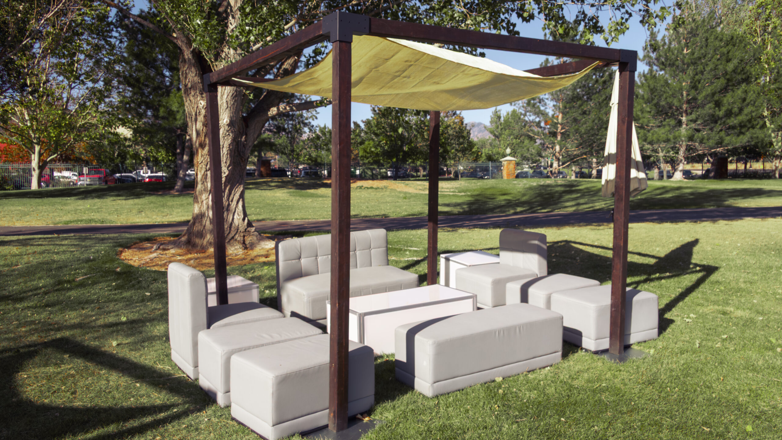 Outdoor lounge setup with modern gray modular seating under a wood canopy, available from In The Event for corporate events, galas, and outdoor gatherings.