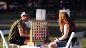Two attendees enjoying a giant Connect Four game at MACU Fest 2025 at Thanksgiving Point during the outdoor festival.