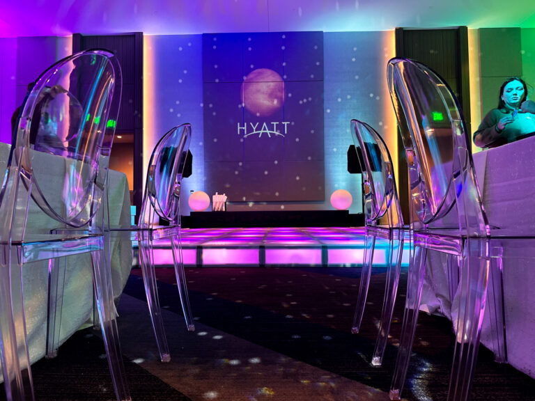 LED-lit ballroom stage with transparent ghost chairs and colorful ambient lighting projected onto walls at the Grand Hyatt Salt Lake City for an Access DMC event by In The Event.