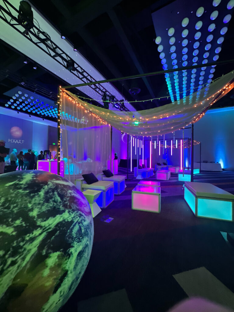 Event lounge with illuminated LED tables, inflatable Earth decor, and draped canopy lighting at Access DMC’s event at the Grand Hyatt Salt Lake City.