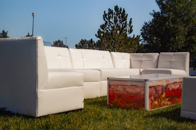 Close-up of a white modular sectional sofa event lounge furniture with a custom coffee table featuring a vibrant, printed landscape graphic for a branded look.