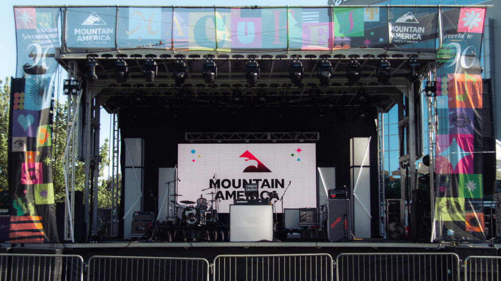 Main concert stage at MACUFest with Mountain America Credit Union branding and colorful festival banners