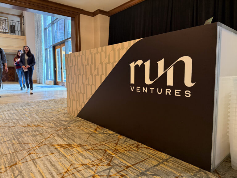 Close-up of a trade show registration or reception desk with custom event signage and branding for 'run ventures.'