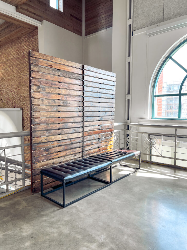 Tufted leather bench with metal frame set against a rustic wood slat wall in a modern event venue designed by In The Event.