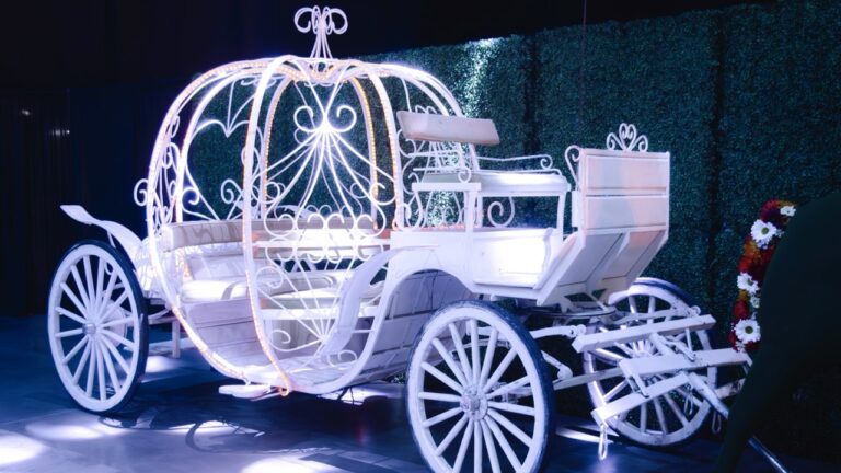 White Cinderella-style carriage with LED lighting and ornate scrollwork, part of a fairytale-themed photo display at the UVU President’s Scholarship Ball.