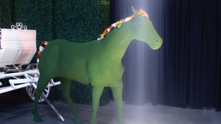 Decorative green horse prop with a colorful floral garland, part of a Cinderella carriage display at the UVU President’s Scholarship Ball.