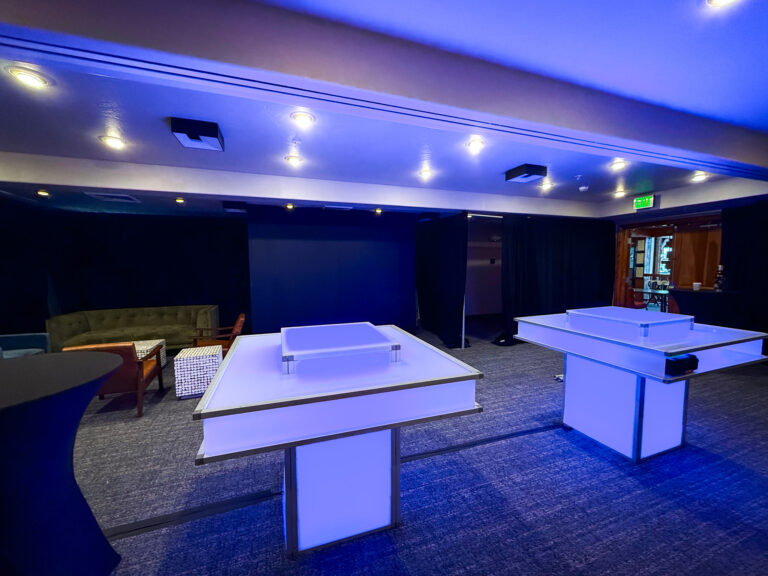 LED furniture rentals featuring illuminated ping pong tables with blue ambient lighting and event lounge furniture in modern corporate event space with custom lighting solutions