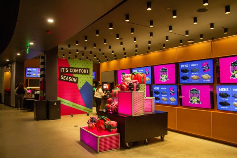 Corporate holiday retail activation featuring branded LED display screens, custom dance floor mods, product merchandising displays, and colorful seasonal graphics