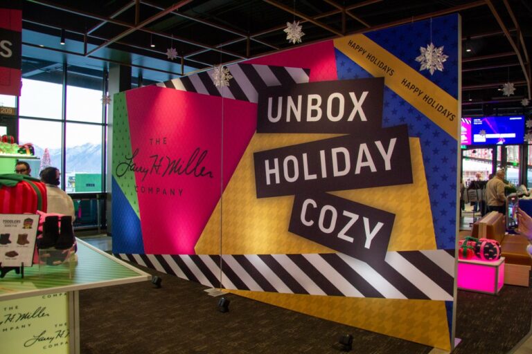 Custom printed holiday event SEG backdrop wall with bold graphics, seasonal messaging, and branded corporate design inside a stadium venue
