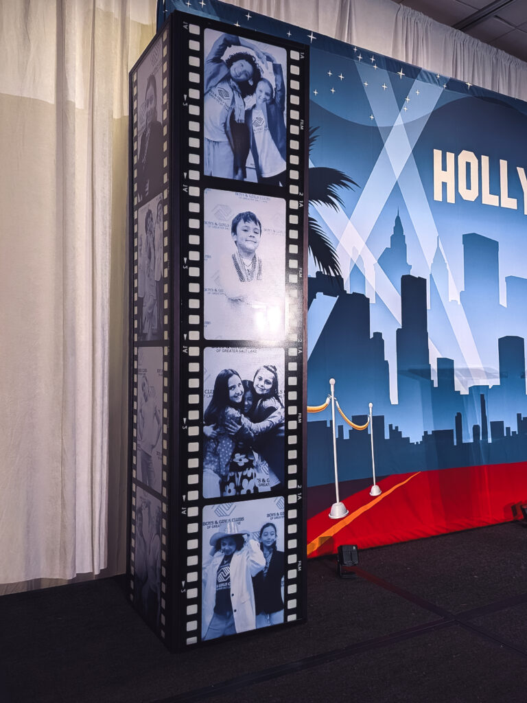 Custom film reel photo display featuring Boys & Girls Club member portraits as part of a Hollywood-themed event stage design.