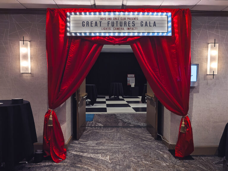 Hollywood-themed gala entrance featuring red drapery and a custom illuminated marquee sign welcoming guests to the Boys & Girls Great Futures Gala.