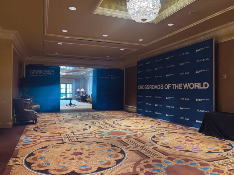 Custom branded entrance portal and step-and-repeat backdrop for the Crossroads of the World International Trade Summit at The Grand America Hotel.