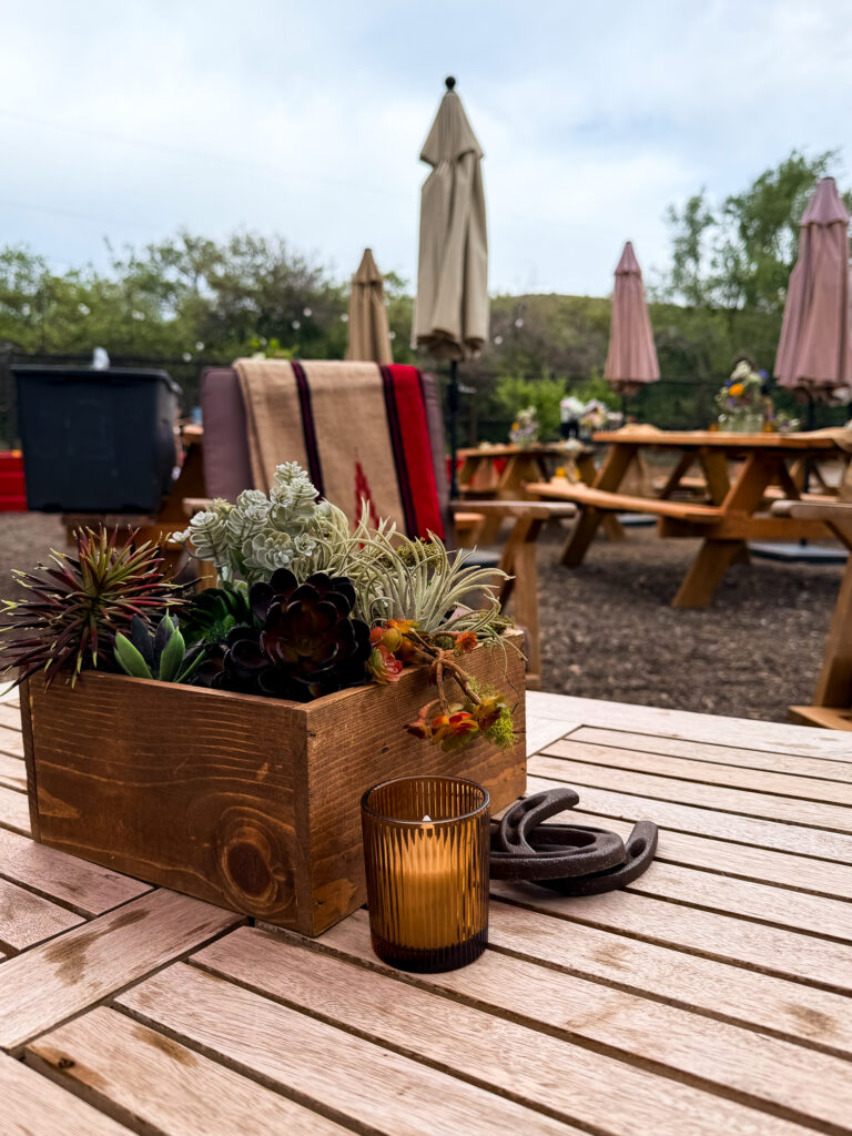 Rustic outdoor lounge table with a succulent centerpiece, amber votive, horseshoes, and Western decor at The Lodge at Blue Sky.