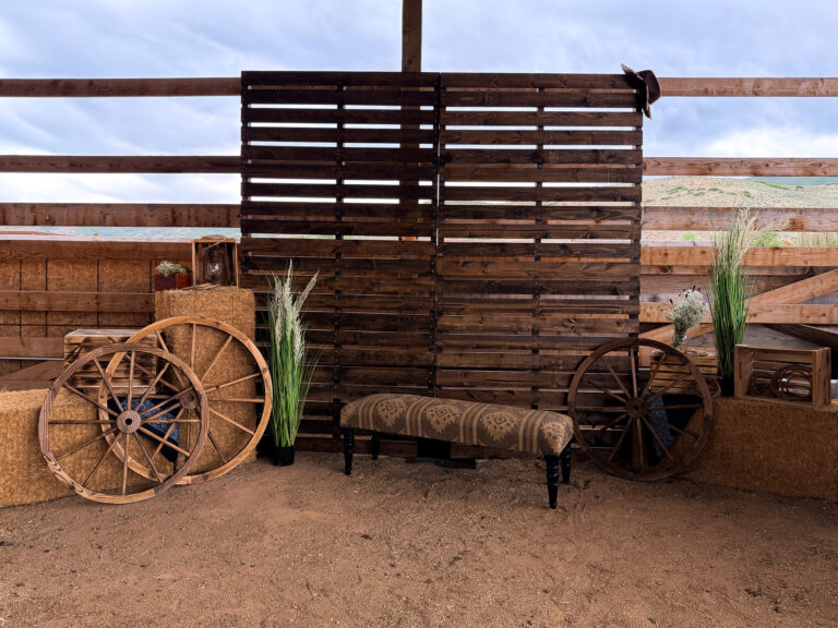 Rustic Western photo backdrop with a reclaimed wood wall, wagon wheels, hay bales, and vintage ranch decor at The Lodge at Blue Sky.