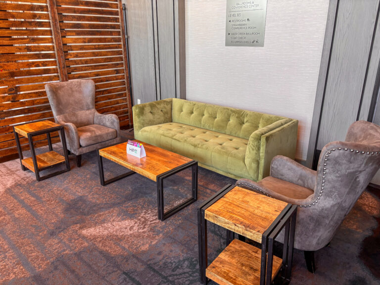 Modern event lounge featuring an olive green velvet Meyers sofa, gray wingback Alton chairs, woodland tables, and industrial side tables by In The Event.