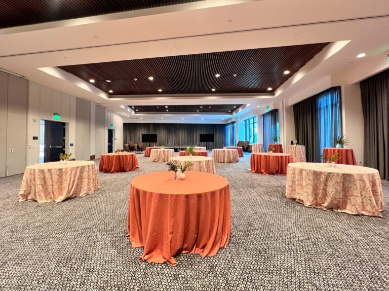 Cocktail reception setup featuring round tables with coral and patterned linens, minimalist centerpieces, and elegant event décor at Le Méridien Salt Lake City Downtown.