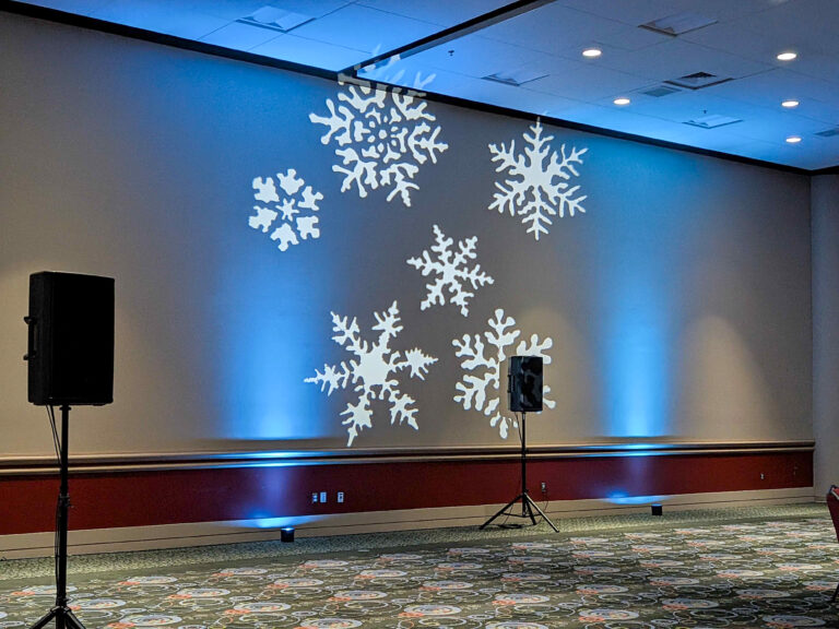 Snowflake gobo lighting projected onto a ballroom wall with blue uplighting for a winter-themed corporate event. NYC26 The Experience