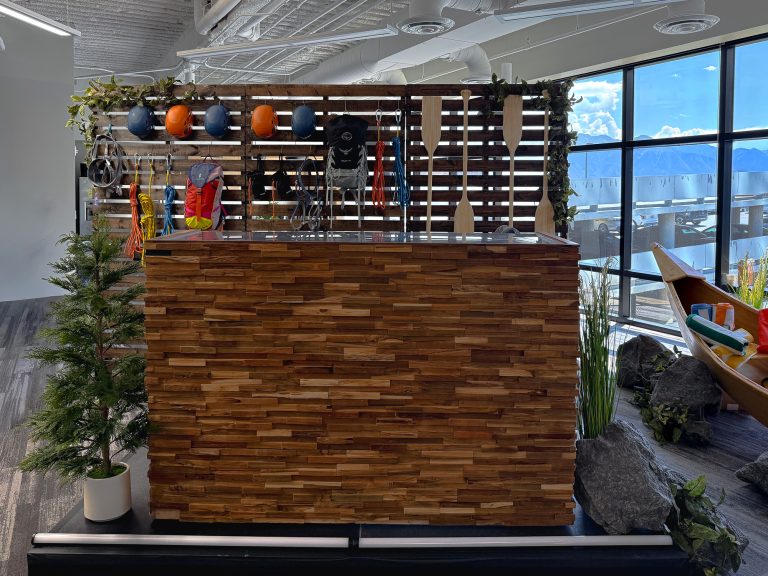 Custom wood-paneled event bar with a rustic gear display featuring helmets, ropes, backpacks, harnesses, and paddles.