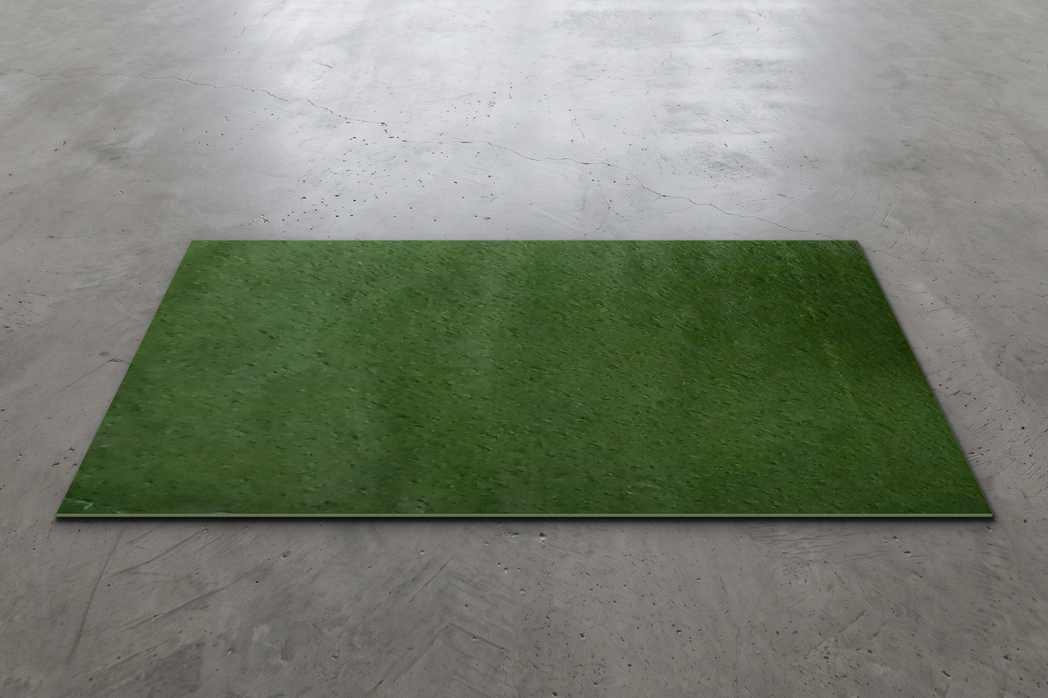 Green artificial turf event rug measuring 76 by 40 inches, shown on a concrete floor