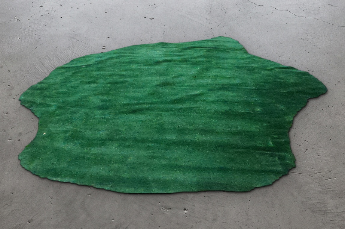 Dark green putting turf cut to an irregular shape, measuring 6.5 by 5.5 feet, shown on a concrete floor